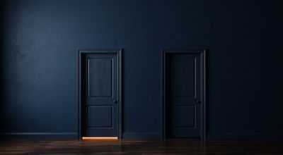 Two identical closed doors, warm amber light showing at the gap beneath the left one and none beneath the right.