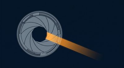 A camera shutter caught at the instant of opening, its blades a narrow crescent with one blade of amber light escaping.